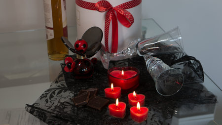 Valentine's Day Romantic Dinner. Date. Table setting with Champagne in two glasses, candles and gift box over holiday red background with heartsの写真素材