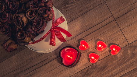 Valentine's Day Romantic Dinner. Date. Table setting with Champagne in two glasses, candles and gift box over holiday red background with heartsの写真素材
