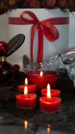 Valentine's Day Romantic Dinner. Date. Table setting with Champagne in two glasses, candles and gift box over holiday red background with heartsの写真素材