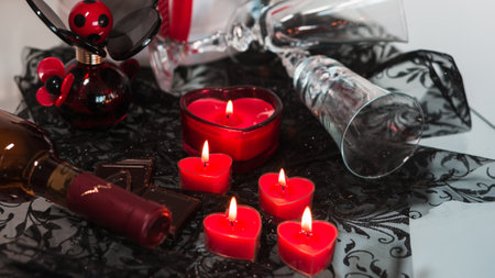 Valentine's Day Romantic Dinner. Date. Table setting with Champagne in two glasses, candles and gift box over holiday red background with heartsの写真素材