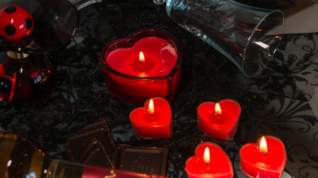 Valentine's Day Romantic Dinner. Date. Table setting with Champagne in two glasses, candles and gift box over holiday red background with heartsの写真素材