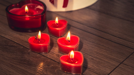 Valentine's Day Romantic Dinner. Date. Table setting with Champagne in two glasses, candles and gift box over holiday red background with heartsの写真素材