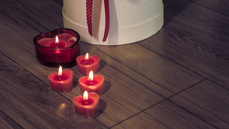Valentine's Day Romantic Dinner. Date. Table setting with Champagne in two glasses, candles and gift box over holiday red background with heartsの写真素材
