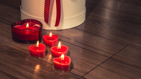 Valentine's Day Romantic Dinner. Date. Table setting with Champagne in two glasses, candles and gift box over holiday red background with heartsの写真素材