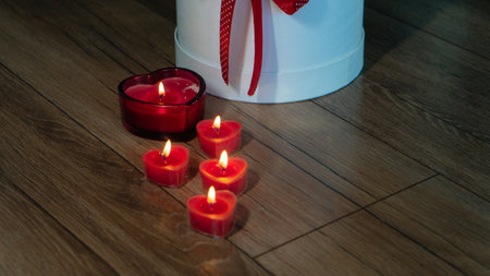 Valentine's Day Romantic Dinner. Date. Table setting with Champagne in two glasses, candles and gift box over holiday red background with heartsの写真素材
