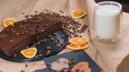slices of chocolate brownie cake with cap milk and coffee beanas on wooden tableの写真素材