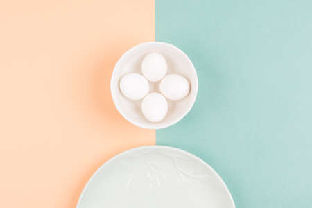 Morden concept of Easter eggs composition on a white plate on two pastel colored background. Flat...