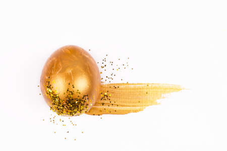 Concept of Easter  festival Egg covered with gold and shines and painted colored spot on white background. Flat lay view.の写真素材