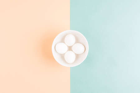 Morden concept of Easter eggs composition on a white plate on two pastel colored background. Flat...