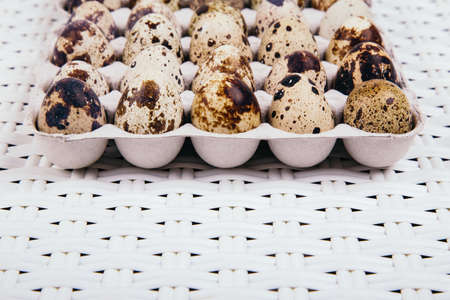 Quail eggs in paper box on white rattan background, side view.の写真素材