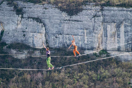 Two men walking along high line above mountains valley. High line contes.