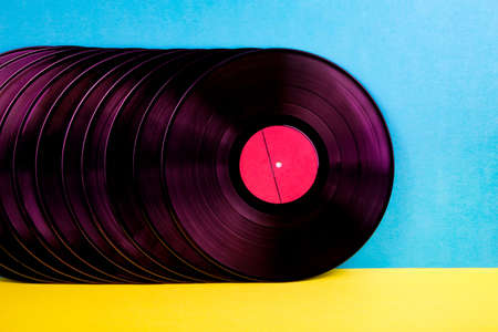 Many black and pink colored vinyl discks placed  in a  line on yellow and blue background.の写真素材