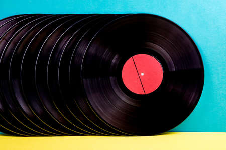 Many black colored vinyl discks placed  in a  line on yellow and blue background.の写真素材