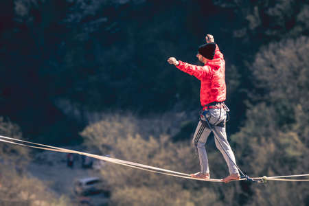 Man in red clothing walking along high line above mountains landscape. High line contest.