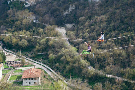 Two men walking along high line above mountains valley. High line contes.