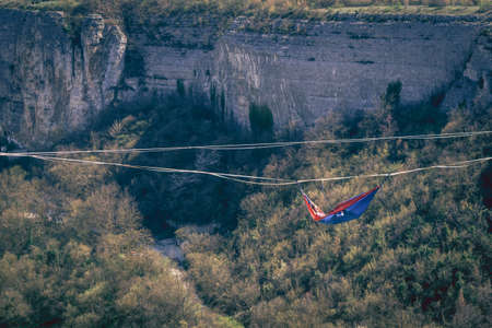Man hanging  in hammock above mountain valley gap. Slack line contest.の写真素材