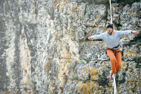 Man in orange pants walking along high line above mountains valley. High line contest.