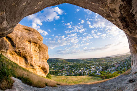 Beautiful landscape of rocks and cave on blue sunset sky background and village infront of it. Crimea peninsula. Bakhchisaray village.の写真素材