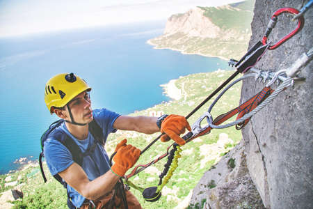 Man belays partner in mountain via ferrata using safety device. Crimea.の写真素材