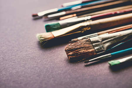 Mass of different paint brusheas on black paper background.の写真素材