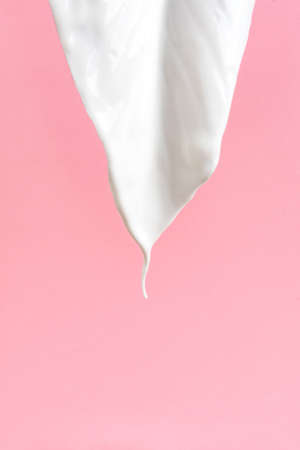 Plant leaf coverd with white acrylic paint looks like pouring milk on pink background.の写真素材