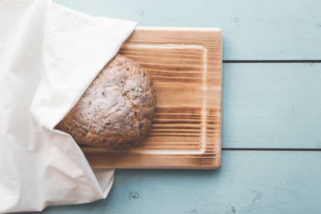 Fresh homemade backed brown bread with seeds and cereals on wooden board and linen background.の写真素材