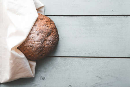 Fresh homemade backed brown bread with seeds and cereals on wooden board and linen background.の写真素材