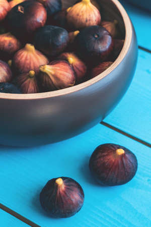 Cropped farme of wooden plate full of ripe figs harvest on a blue wooden table.の写真素材