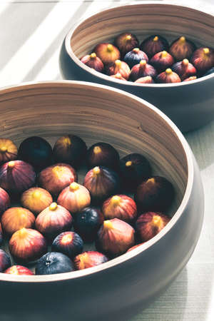 Two wooden plate full of ripe figs harvest on a table.の写真素材