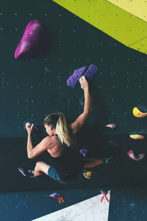 Young athletic woman climbing in boulder gym. Back view.の写真素材