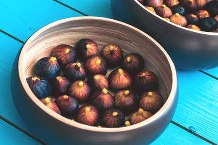 Two wooden plate full of ripe figs harvest on a blue wooden table.の写真素材