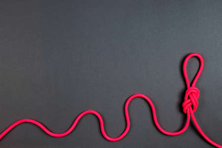 Vivid colored alpine rope knot on dark grey background.の写真素材
