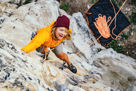 Young woman climbs an overhanging rock  with rope. Sport climbing, lead. Upper view.の写真素材