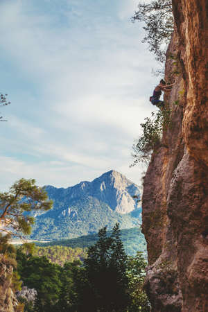 Young athletic woman climbs an overhanging rock with rope in Turkey. Sport climbing, lead. Upper view.の写真素材
