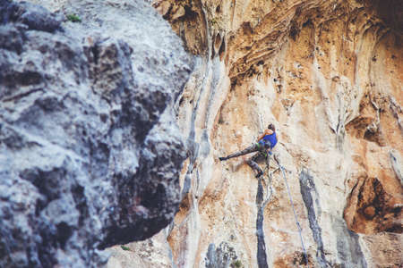 Young athletic woman climbs an overhanging rock with rope in Turkey. Sport climbing, lead. Upper view.の写真素材