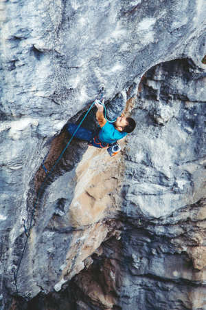 Athletic man climbs very high tufa rock with rope in Turkey. Sport climbing, lead.の写真素材