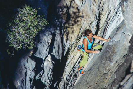 Young athletic woman climbs an overhanging rock with rope in Turkey. Sport climbing, lead. Upper...