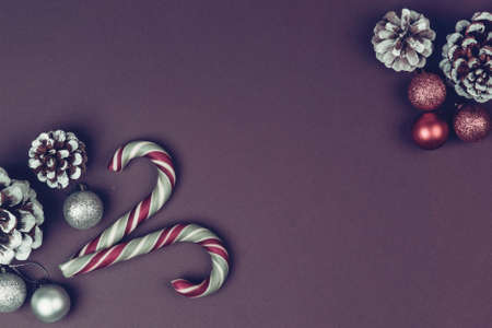 New year composition made of christmas balls, cones and striped hard candies on violet background....