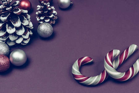 New year composition made of christmas balls, cones and striped hard candies on violet background. Flat lay style.の写真素材