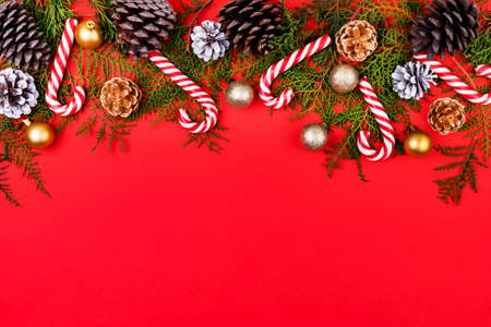 New year composition made of christmas balls, cones and striped hard candies on red background. Flat...