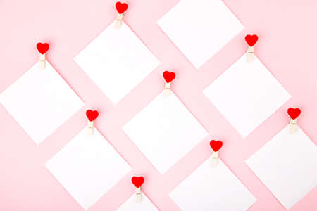 White blank square shape stickers with heart pins on cute pink background, Valentine's day card design. Flat lay style.の写真素材