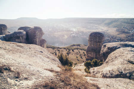 Sunny landscape of curious limestone rocks and small town down hill. Old city Bakhchisaray, Crimea.