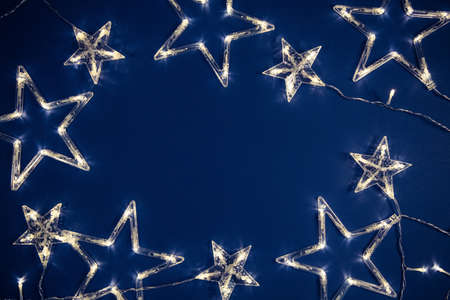 Star shaped garland lights on classic blue color trend of 2020 background. Festive project backdrop.の写真素材