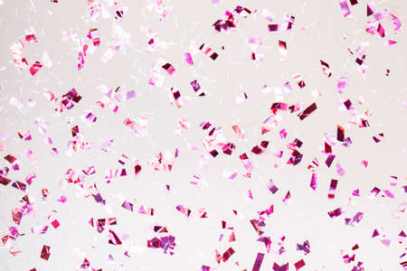 Glittering purple confetti on light pastel trendy background. Festive background for projects.の写真素材