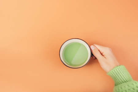 Female hands holding cup of green japanese matcha tea with milk. Organic product.の写真素材