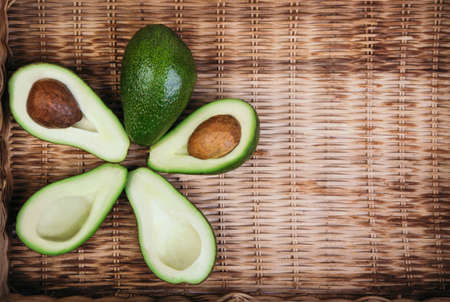 Flat lay composition of cut avocado halfs on wooden tray background. Healthy organic food.