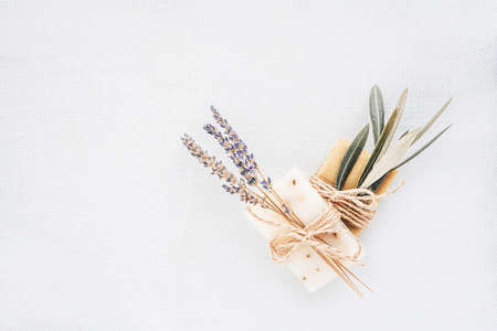 Two pieces of natural organic lavender and olive soap packed with dried lavender and olive branch on light linen background. Organic spa set.の写真素材