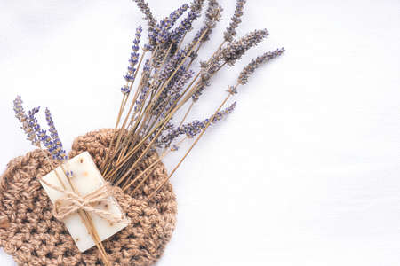 Piece of natural organic lavender soap packed with dried lavender branch and jute washcloth on light linen background. Organic spa set.の写真素材