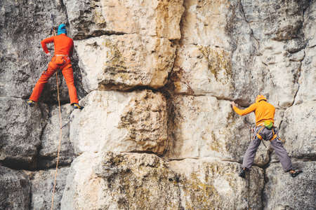 Athletic woman and man in colorful sportswear climbs a rock with rope. Sport climbing, lead. Side view. Crimea.の写真素材