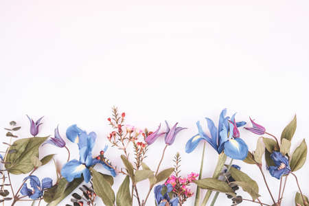 Flower card made of blue colored iris  flowers  with white blank paper in the cennter. For holiday...